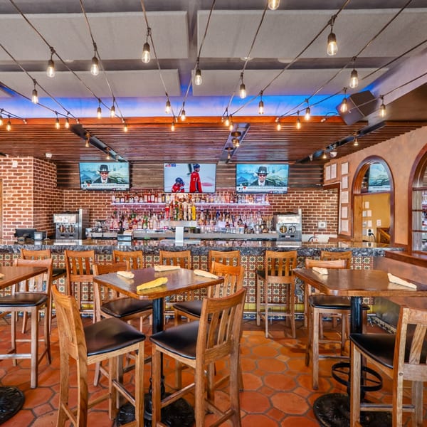 Interior of Guapo's Cocina & Bar, featuring a well-stocked bar, high-top tables, and string lights.