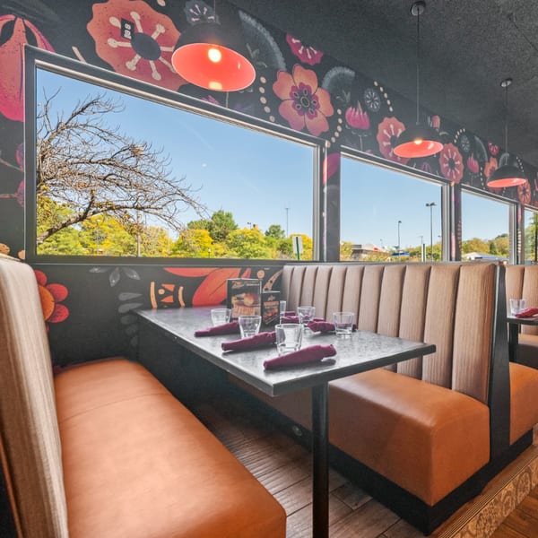Guapo's Cocina & Bar dining area with brown booths, set tables, and floral wallpaper.