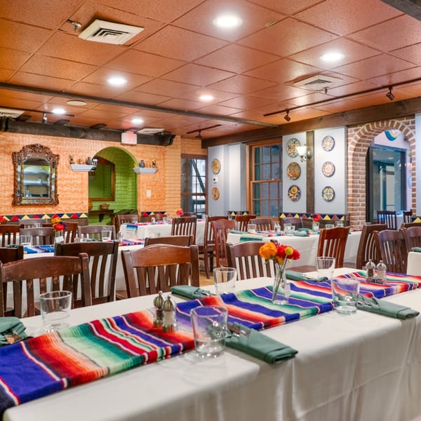 Interior of Guapo's Cocina & Bar, featuring dining tables with colorful runners and Mexican decor.