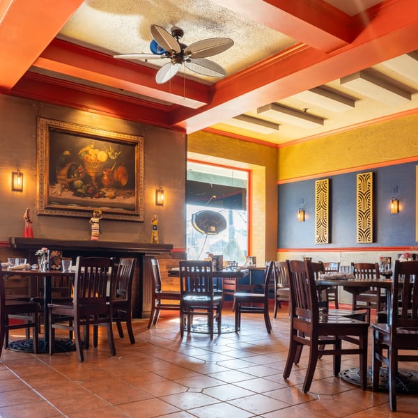 Inviting dining room at Guapo's Cocina & Bar with colorful walls, wooden tables, and a large painting.