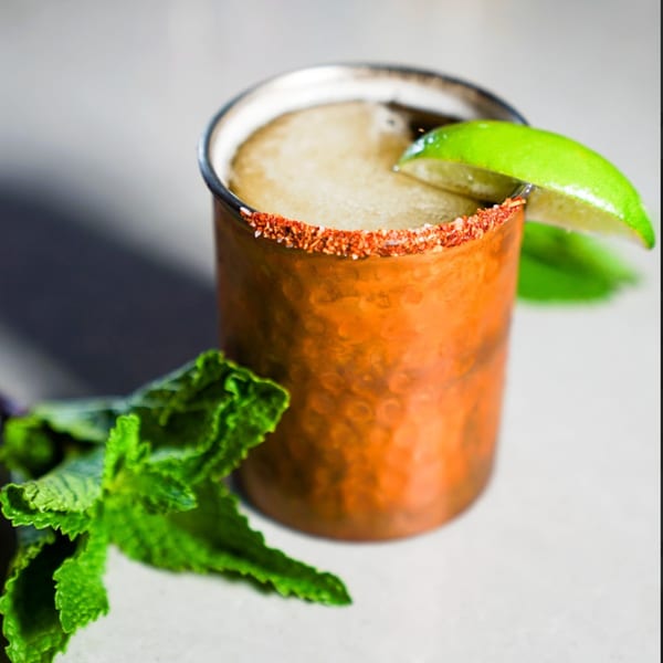 A Guapo's Cocina & Bar Mexican mule cocktail in a copper mug with a lime wedge and mint.