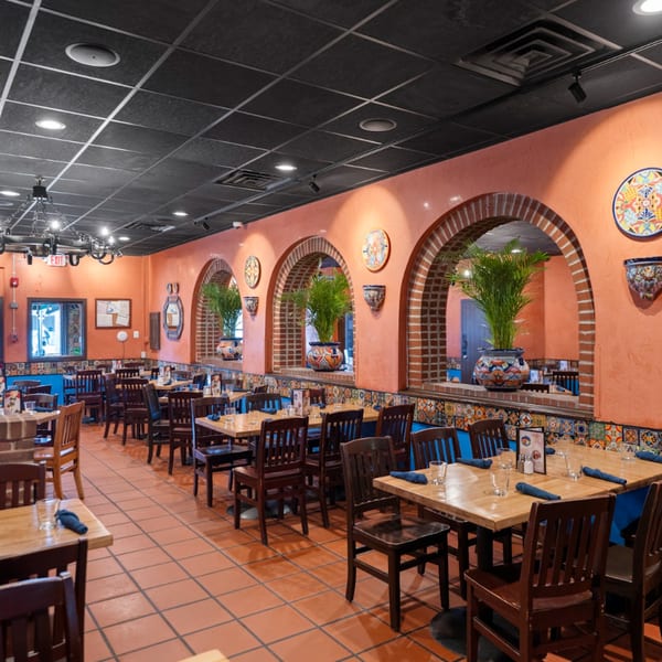 Guapo's Cocina & Bar dining room with orange walls, brick arches, tiled accents, and wooden tables.