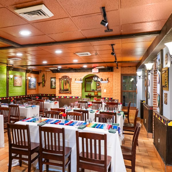 Guapo's Cocina & Bar dining room with colorful Mexican decor, set tables, and brick walls.