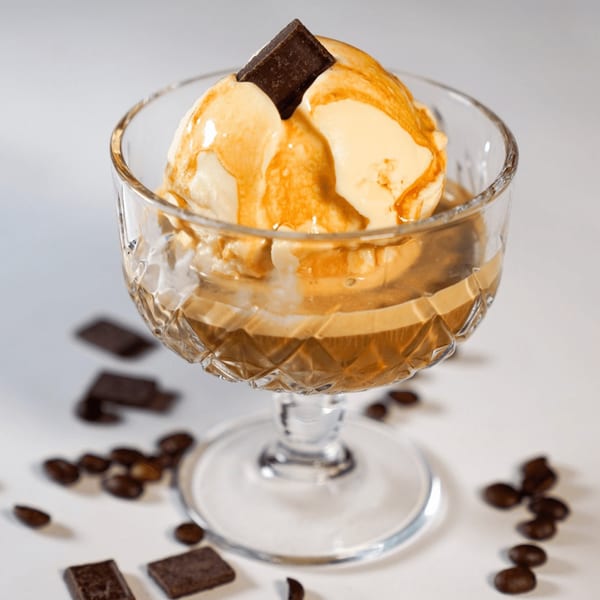 Affogato dessert with vanilla ice cream, espresso, and a chocolate square in a crystal glass.