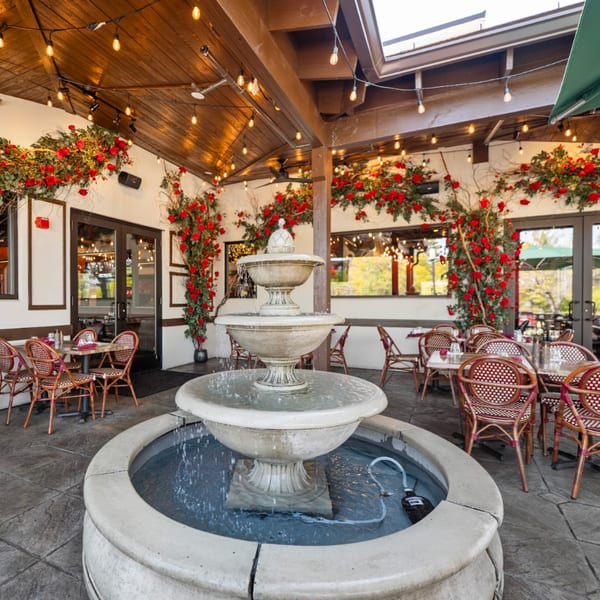 Guapo's Cocina & Bar's outdoor patio with a tiered fountain, string lights, and red floral decor.