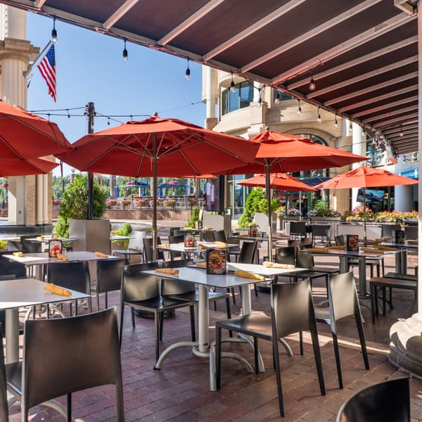 Guapo's Cocina & Bar's outdoor patio with red umbrellas, tables, and chairs on a sunny day.