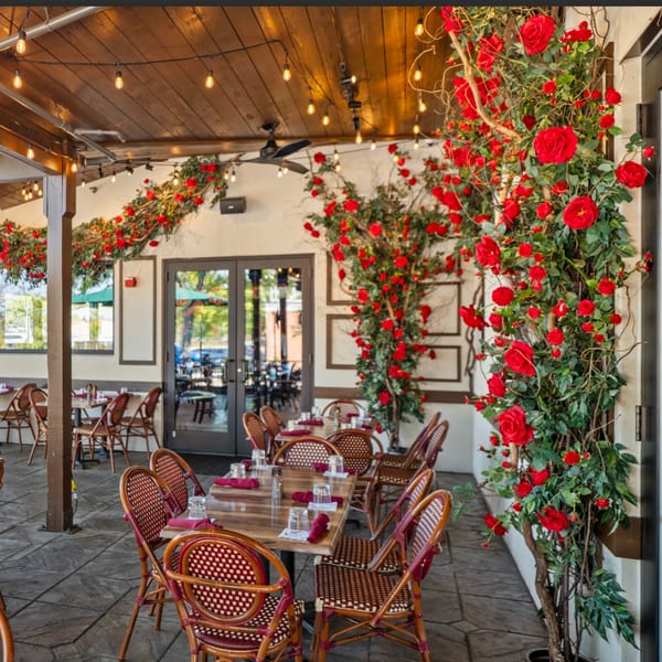 Guapo's Cocina & Bar's outdoor patio with tables, chairs, string lights, and red rose decorations.