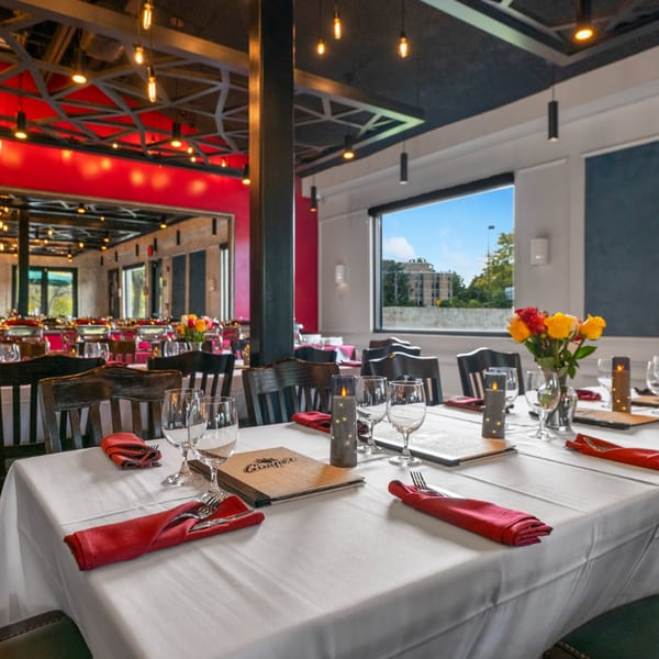 Elegant dining room at Guapo's Cocina & Bar with set tables, red accents, and large windows.