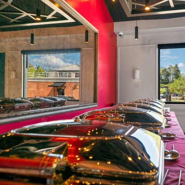 Guapo's Cocina & Bar buffet line with shiny chafing dishes on a red tablecloth.