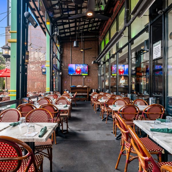 Guapo's Cocina & Bar's outdoor patio with rows of tables and chairs, and TVs on the back wall.