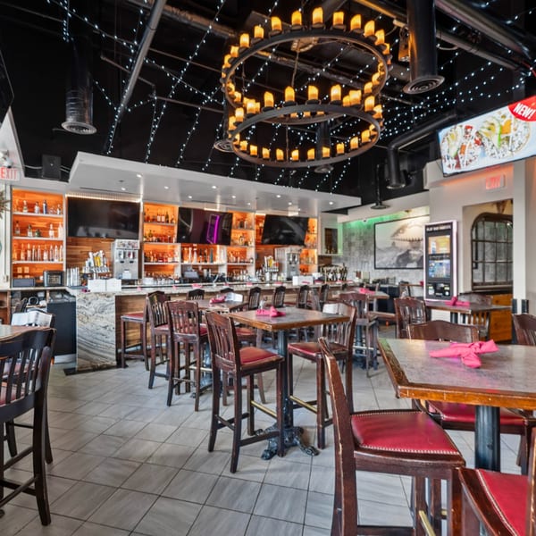 Guapo's Cocina & Bar interior with a large bar, high-top tables, and a circular chandelier.