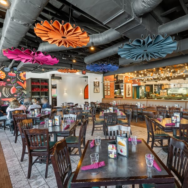 Spacious dining room at Guapo's Cocina & Bar with colorful ceiling decor, dark tables, and patterned floor.