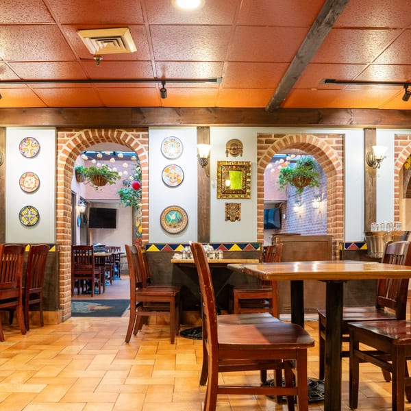 Interior of Guapo's Cocina & Bar, featuring brick archways, decorative plates, and wooden tables.