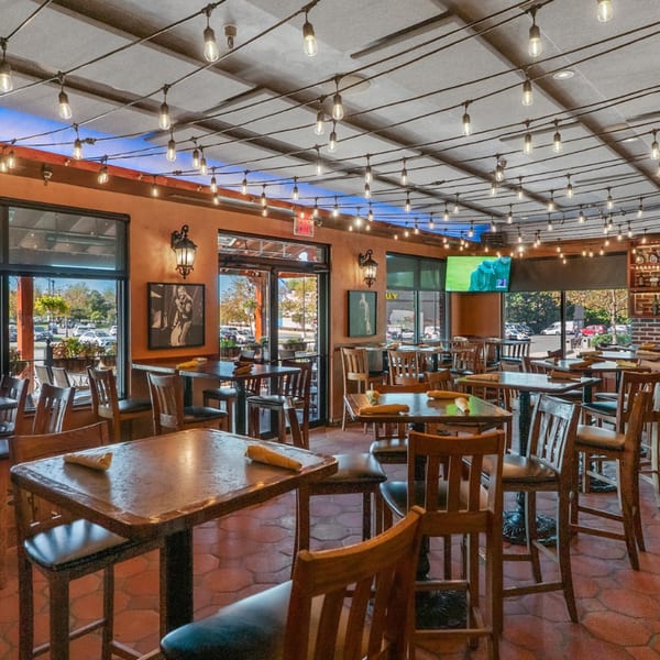 Guapo's Cocina & Bar's dining room with string lights, high-top tables, and large windows.