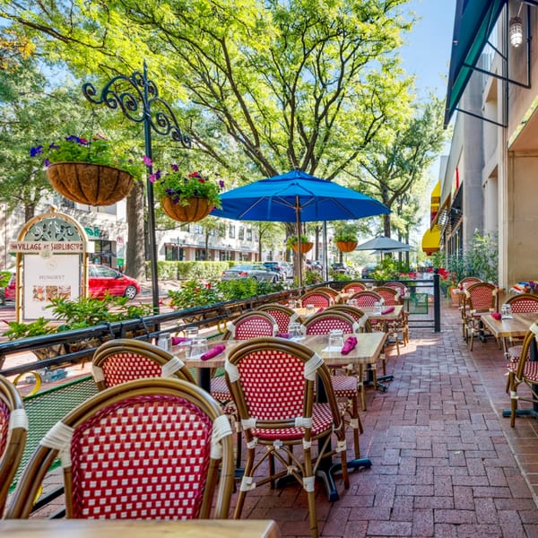 Outdoor patio of Guapo's Cocina & Bar with red and white chairs, wooden tables, and blue umbrellas.