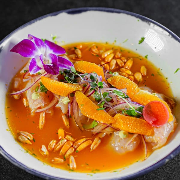 Guapo's Cocina & Bar ceviche with orange slices, red onion, corn, and a purple orchid garnish.