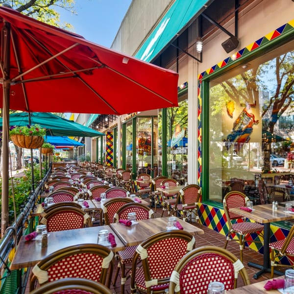 Guapo's Cocina & Bar's vibrant outdoor patio with red and teal umbrellas, and colorful Mexican-themed decor.