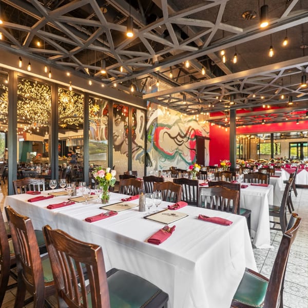 Guapo's Cocina & Bar dining room with white tablecloths, red napkins, and vibrant wall murals.