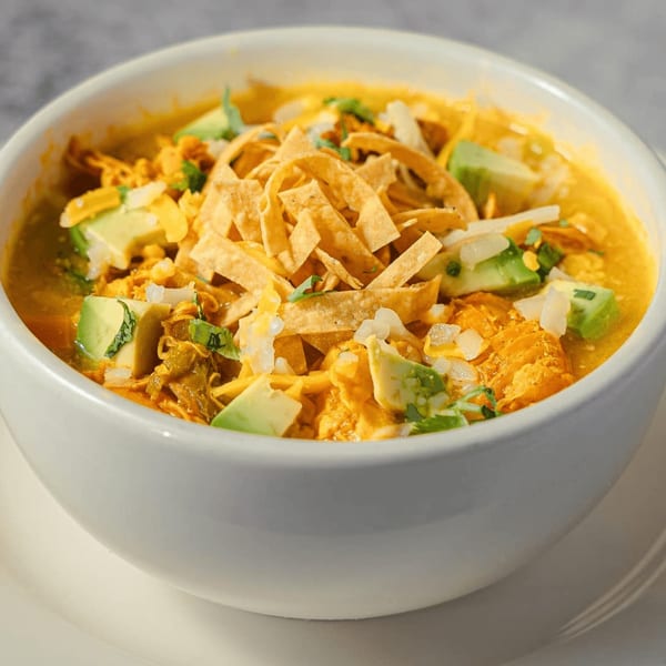 A bowl of Guapo's Mexican chicken tortilla soup with avocado, cheese, and tortilla strips.