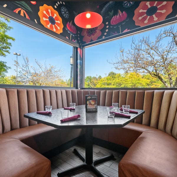 A Guapo's Cocina & Bar booth with a table set for four, featuring a vibrant floral ceiling.