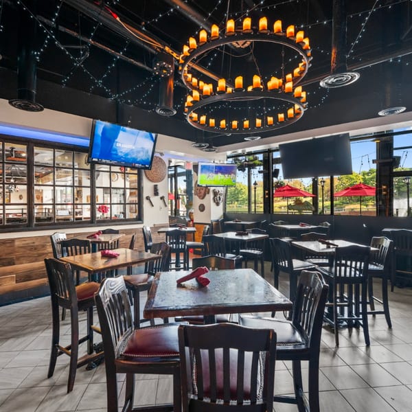 Guapo's Cocina & Bar dining room with high-top tables, TVs, and a large candle chandelier.