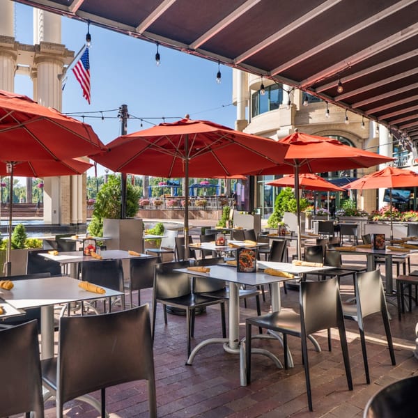 Guapo's Cocina & Bar's outdoor patio features red umbrellas, tables, and chairs on a sunny day.