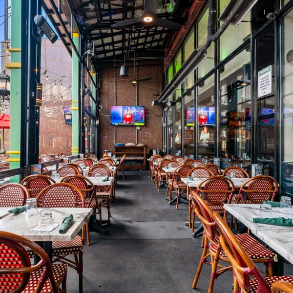 Outdoor patio dining area at Guapo's Cocina & Bar with red and white woven chairs and marble tables.