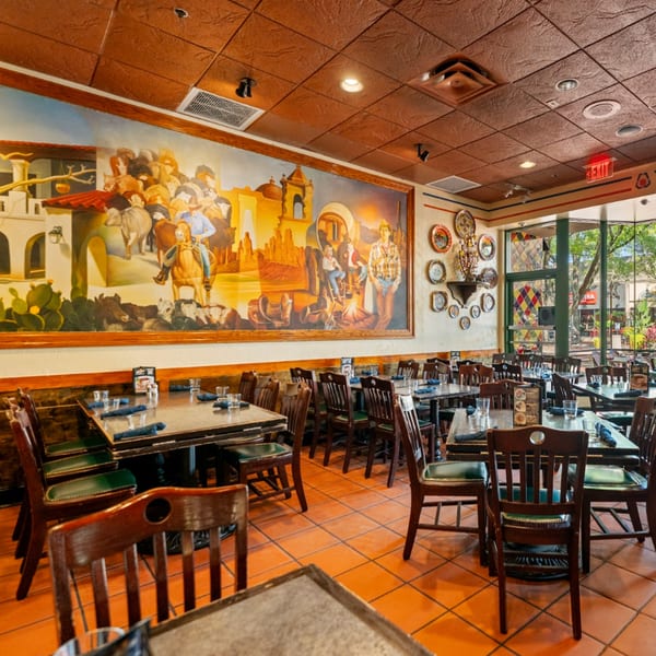 Guapo's Cocina & Bar dining room with a large mural, tables, chairs, and a window view.