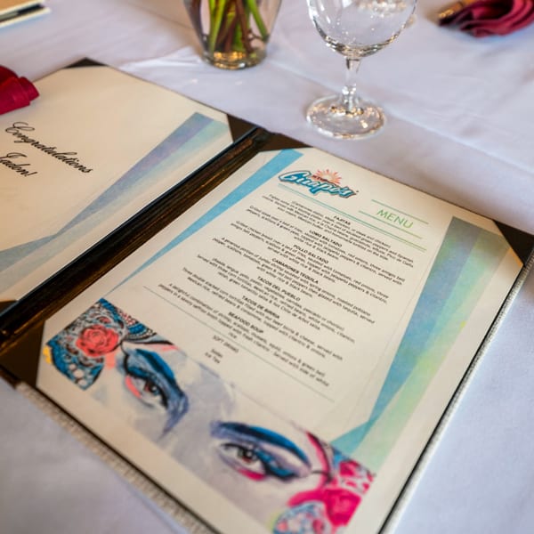 Guapo's Cocina & Bar menu with "Congratulations Jaden!" card and wine glass on a white tablecloth.