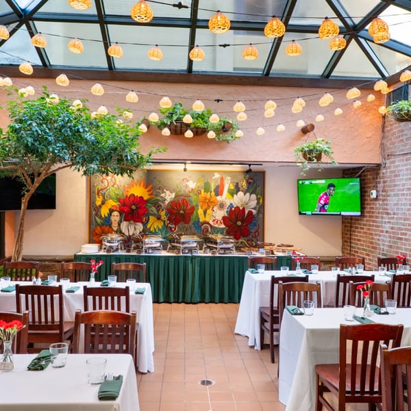 Guapo's Cocina & Bar dining room with buffet, colorful mural, and string lights under a skylight.
