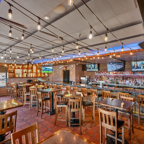 Guapo's Cocina & Bar's interior with a long bar, high-top tables, and string lights.