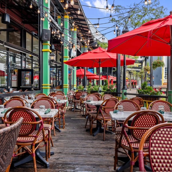 Outdoor patio of Guapo's Cocina & Bar with red umbrellas, string lights, and empty tables with chairs.
