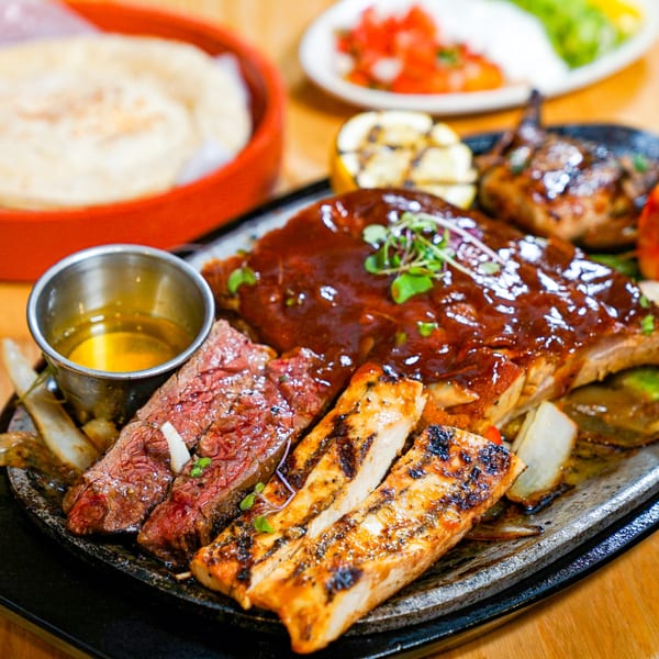 Sizzling platter of Guapo's Mexican grilled steak, chicken, and ribs with onions and peppers.