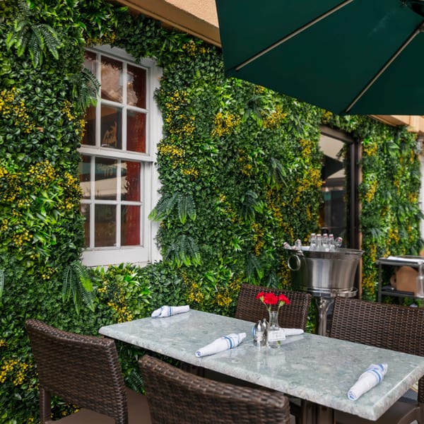 Guapo's Cocina & Bar outdoor patio with a table, chairs, and a lush green wall.
