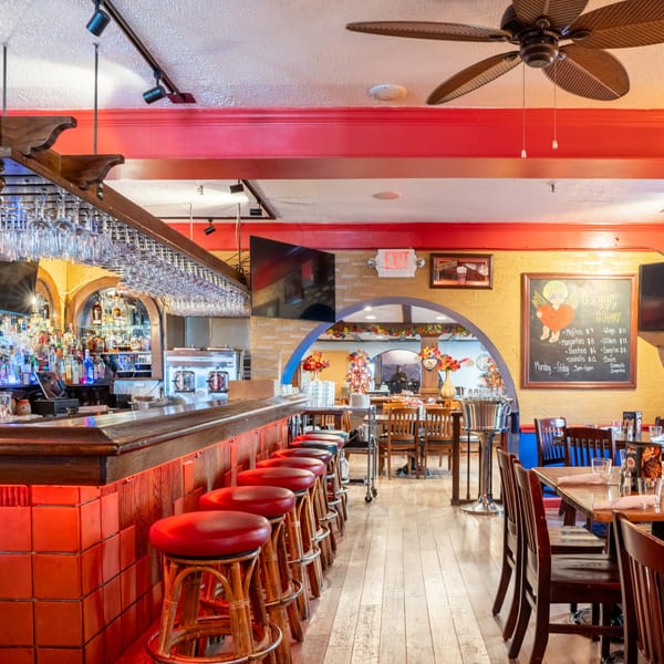 Interior of Guapo's Cocina & Bar, featuring a long bar with red stools and a dining area.