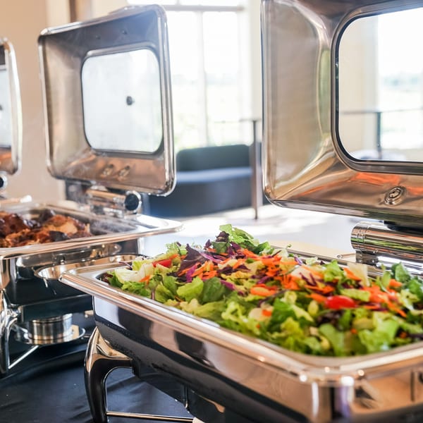 Fresh salad with mixed greens, carrots, and red cabbage in a chafing dish at Guapo's buffet.
