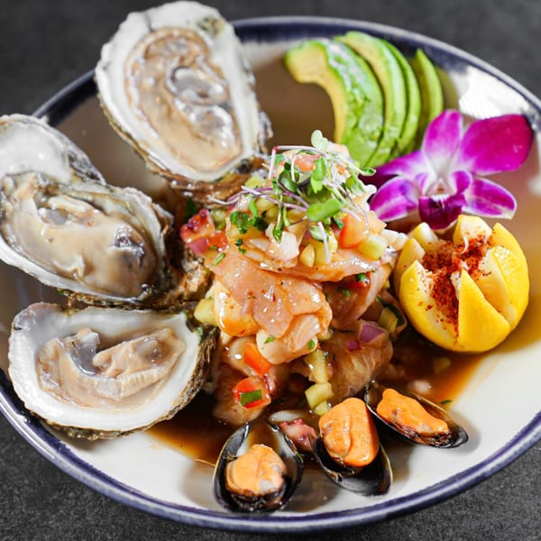 Guapo's Cocina & Bar's seafood platter with oysters, ceviche, mussels, avocado, and a purple orchid.