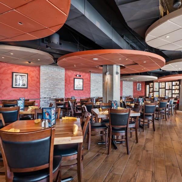 Interior of Guapo's Cocina & Bar, featuring wooden tables, black chairs, and red and brick walls.