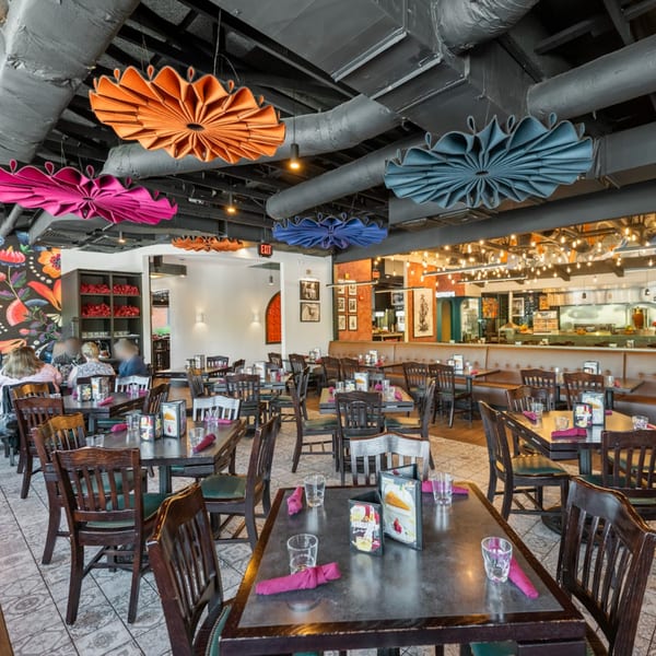 Guapo's Cocina & Bar dining room with colorful ceiling decor, tables, chairs, and a visible kitchen.