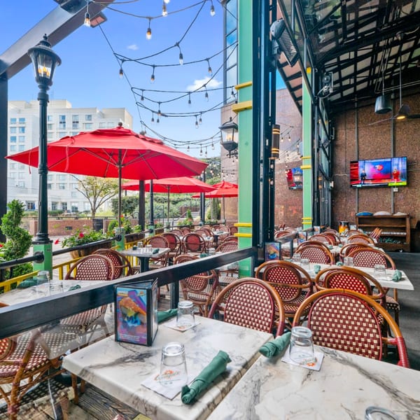 Guapo's Cocina & Bar's outdoor patio with red umbrellas, string lights, and empty tables with chairs.