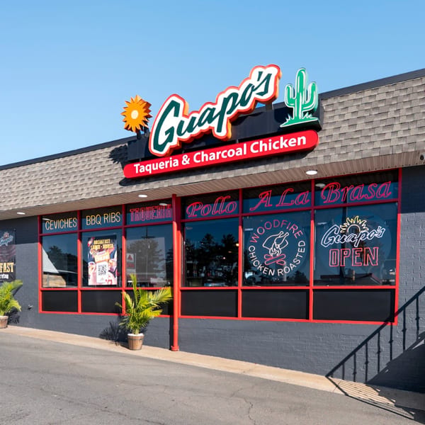 The exterior of Guapo's Taqueria & Charcoal Chicken, featuring a large sign and window decals.