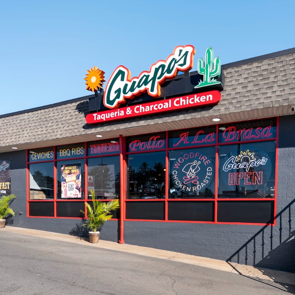 The exterior of Guapo's Taqueria & Charcoal Chicken, featuring a large sign and window decals.